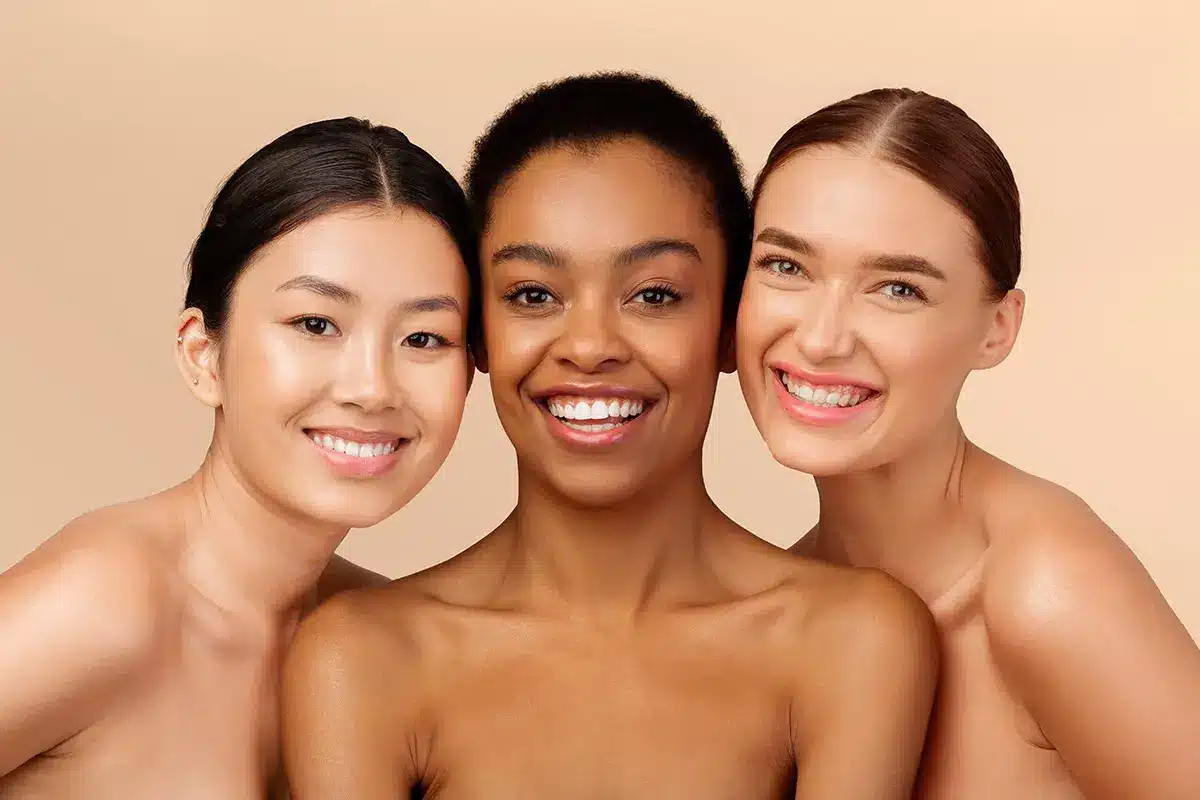 three multicultural ladies models posing smiling at camera on beige studio background three multicultural ladies models posing smiling at camera on beige studio background
